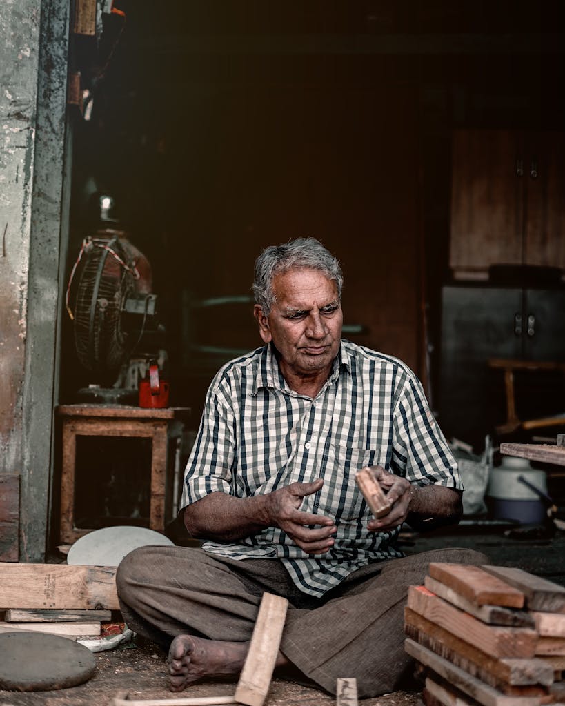 South Asian craftsman working with wood in a rustic workshop in Kalol, India.